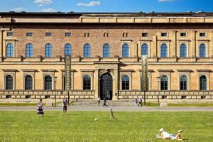Alte Pinakothek - München - Außenansicht des Museumsgebäudes mit Besuchern auf der davorliegenden Liegewiese