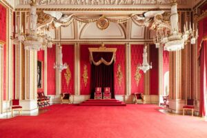 Buckingham Palace - London - Thronsaal: Ein grandioser Raum mit rot-goldener Dekoration, prunkvollen Säulen, zwei prominenten Thronsesseln auf einem Podest