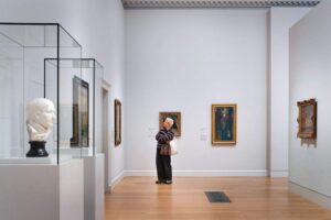 Courtauld Gallery - London -Kunstgalerie: Ein heller Galerieraum mit einer weißen Marmorbüste im Vordergrund und Gemälde an weißen Wänden