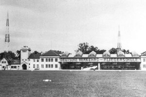 Deutsches Museum Flugwerft Schleißheim - Historisches Schwarz-Weiß-Foto des Gebäudekomplexes der Deutschen Verkehrs-Fliegerschule im Jahr 1930 mit geöffneten Hangartoren und Antennenmasten