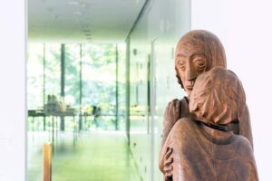 Ernst Barlach Haus - Hamburg - Holzskulptur: Nahaufnahme der bedeutenden Skulptur'Das Wiedersehen' von Ernst Barlach mit Blick durch den Ausstellungsraum