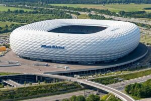 FC Bayern Museum - München - Allianz Arena: Luftaufnahme des Stadions mit der charakteristischen weißen Wabenstruktur der Fassade