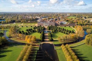 Hampton Court Palace - London - Luftaufnahme: Blick über die symmetrische Parkanlage mit kegelförmigen Eiben und dem Long Water Kanal auf das Schlossgebäude
