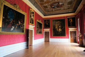 Kensington Palace - London - King's Gallery: Prächtig verzierte rote Wände, großformatige Ölgemälde und eine kunstvoll bemalte Decke