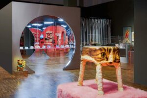 Museum am Rothenbaum - Hamburg - Ausstellung - Katzen!: Ein Hocker im Katzen-Design steht auf einem rosa Teppich vor einem runden Wanddurchbruch