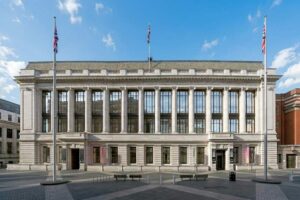 Science Museum - London - Außenansicht: Die neoklassizistische Steinfassade des Museumsgebäudes mit großen Fensterfronten, Säulen und drei gehissten Flaggen