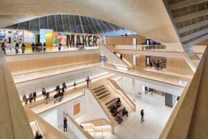 The Design Museum - London - Innenarchitektur: Das weitläufige, helle Atrium mit markanten Treppen aus hellem Holz und mehreren Ebenen im modernen Museumsgebäude