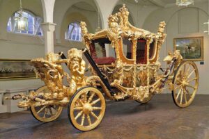 The Royal Mews - London - Gold State Coach: Die legendäre goldene Staatskutsche aus dem Jahr 1762 mit ihren überbordenden Barock-Verzierungen, drei vergoldeten Engeln auf dem Dach und prächtigen Malereien an den Seitenwänden