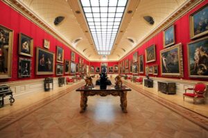 The Wallace Collection - London - Große Galerie: Blick in den opulenten Saal mit intensiv roten Wänden, Goldrahmen-Gemälden, einem Glasdach und historischen Möbeln