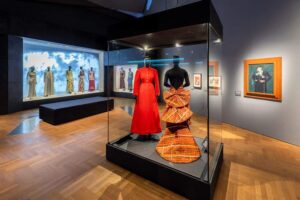 Victoria and Albert Museum (V&A) - South Kensington - London - Ausstellung Schiaparelli - Fashion becomes Art: Ein markantes rotes Designerkleid in einer Glasvitrine inmitten avantgardistischer Modeentwürfe
